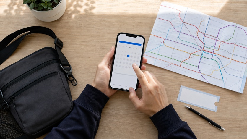 スマートフォンと路線図を使って観戦日程を確認する人