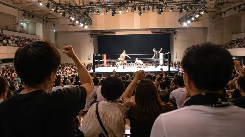 屋内会場のリングで行われるプロレスを観戦する観客